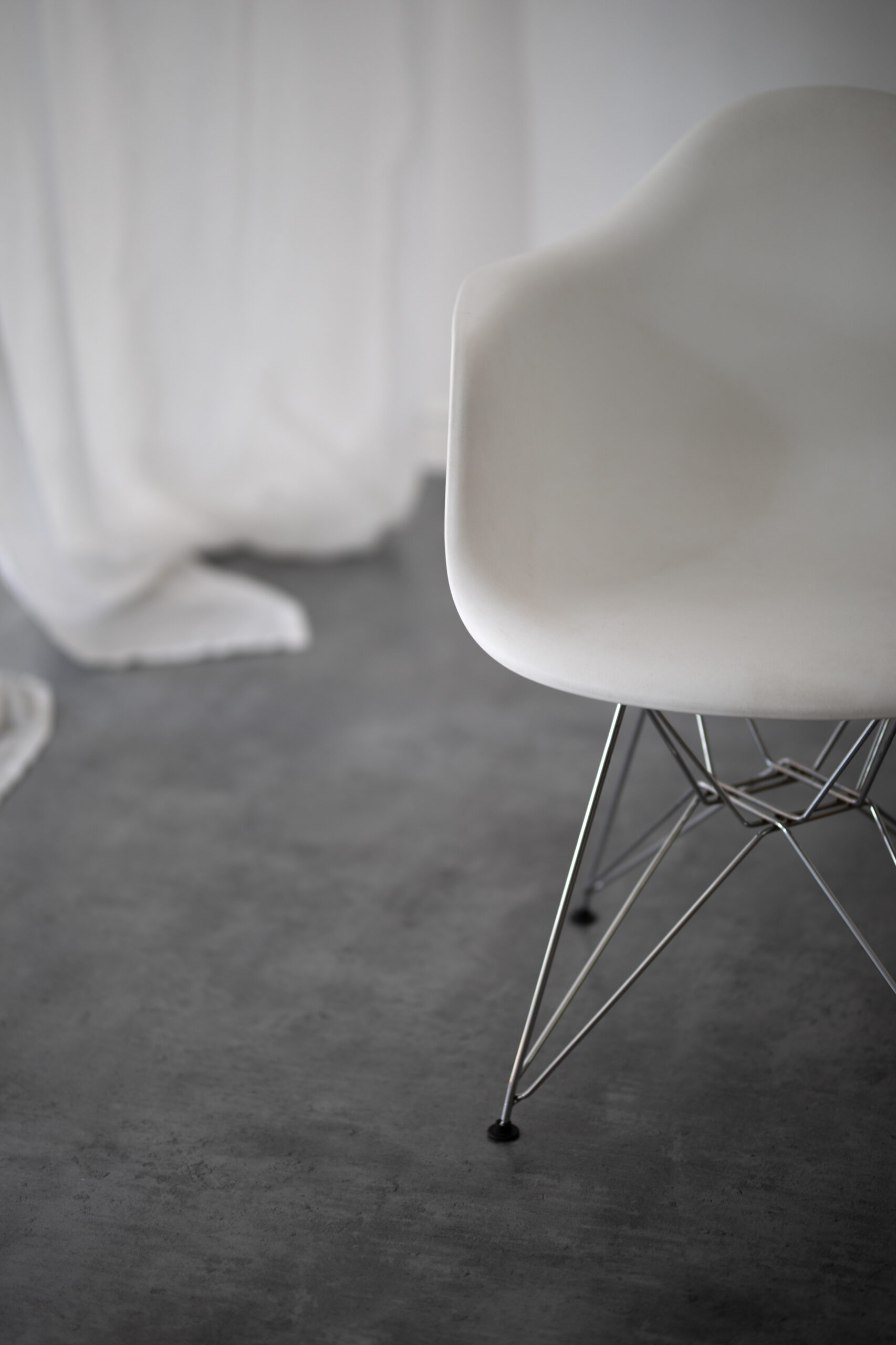 białe krzesło plastikowe na metalowych nogach stojące na betonowej podłodze